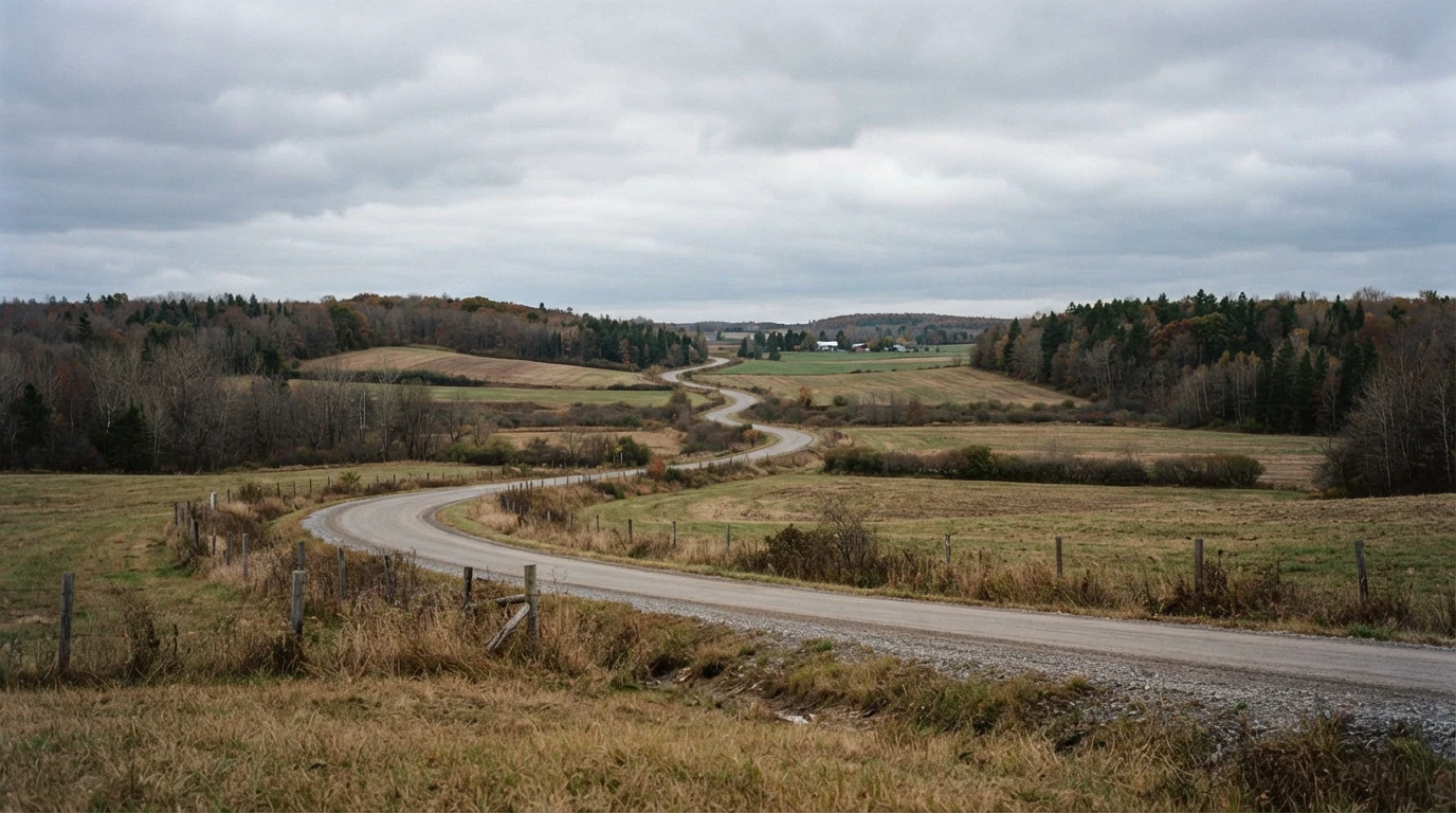 Quiet country road winding through rolling rural Northumberland County fields in late autumn.